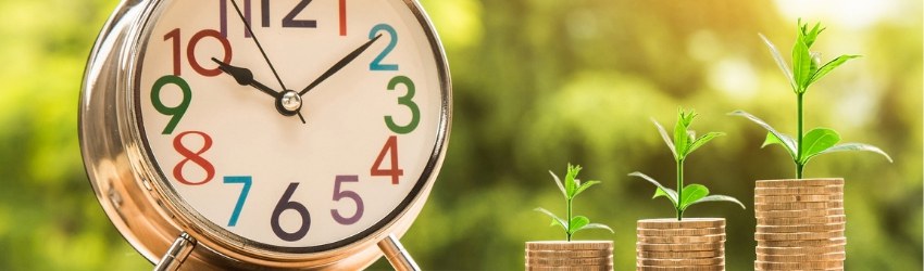 Sveglia con accanto pile di monete di differenti altezze che germogliano