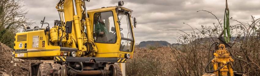 permesso costruzione suolo pubblico: escavatore guidato da un uomo che sta lavorando in un terreno agricolo