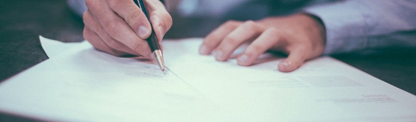 Permesso di costruzione casi: mani di uomo che firmano un documento poggiato su un tavolo